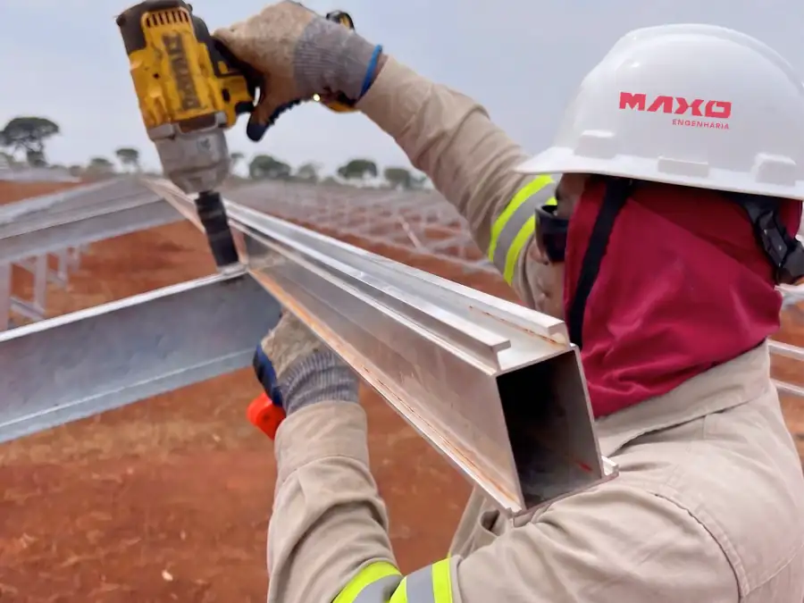 Técnico com capacete da Maxo montando o perfil metálico de uma estrutura solar